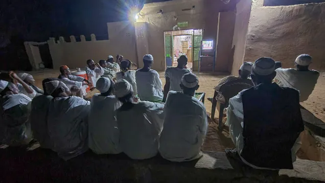 مواطنون يشاهدون التلفاز أمام دكان في أم درمان.jpg